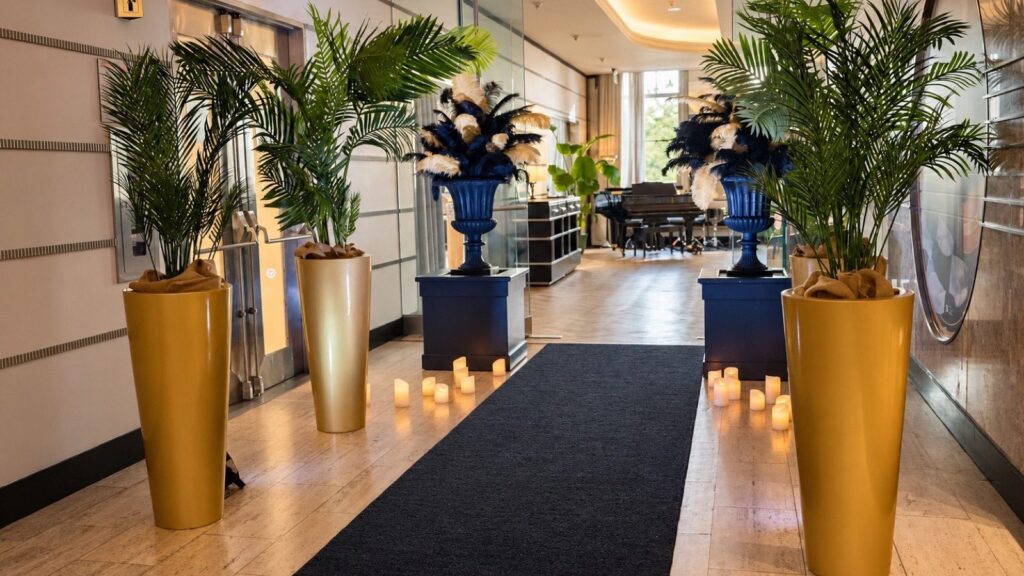 Event entrance at Le 9e: black carpet framed by palm trees in gold vases and candles.
